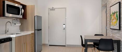 A modern kitchen with a built-in microwave, dishwasher, and refrigerator. There is a dining area with a table and chairs.
