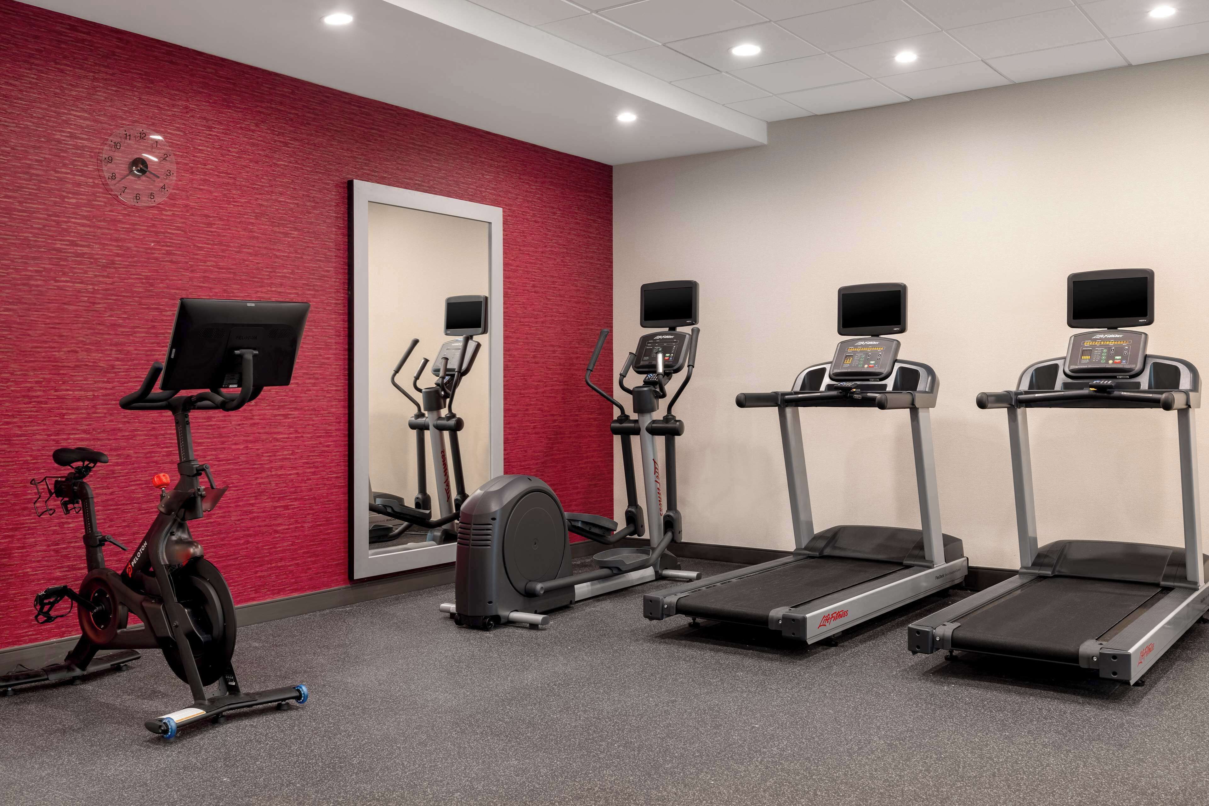 Un gimnasio con cintas de correr, elípticas y una bicicleta estática.