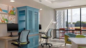 Een moderne kantoorruimte met een groot blauw kastmeubel, twee bureaus met computers en kleurrijke stoelen.
