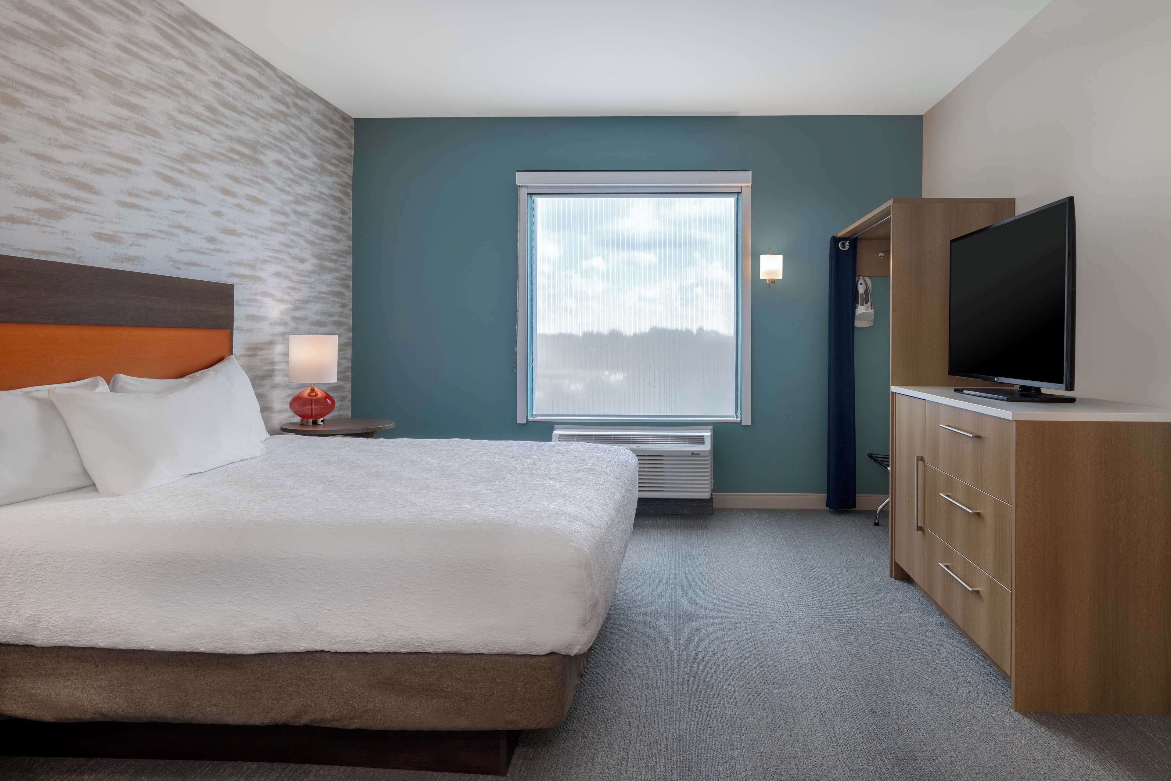 Habitación de hotel con una cama grande, televisión, armario y ventana con vistas.