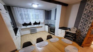 A modern kitchen with white cabinets, a black countertop, and a window with decorative curtains.