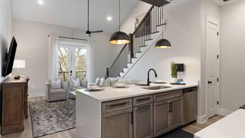 A modern kitchen with a central island, built-in cabinets, and a staircase leading to an upper level.
