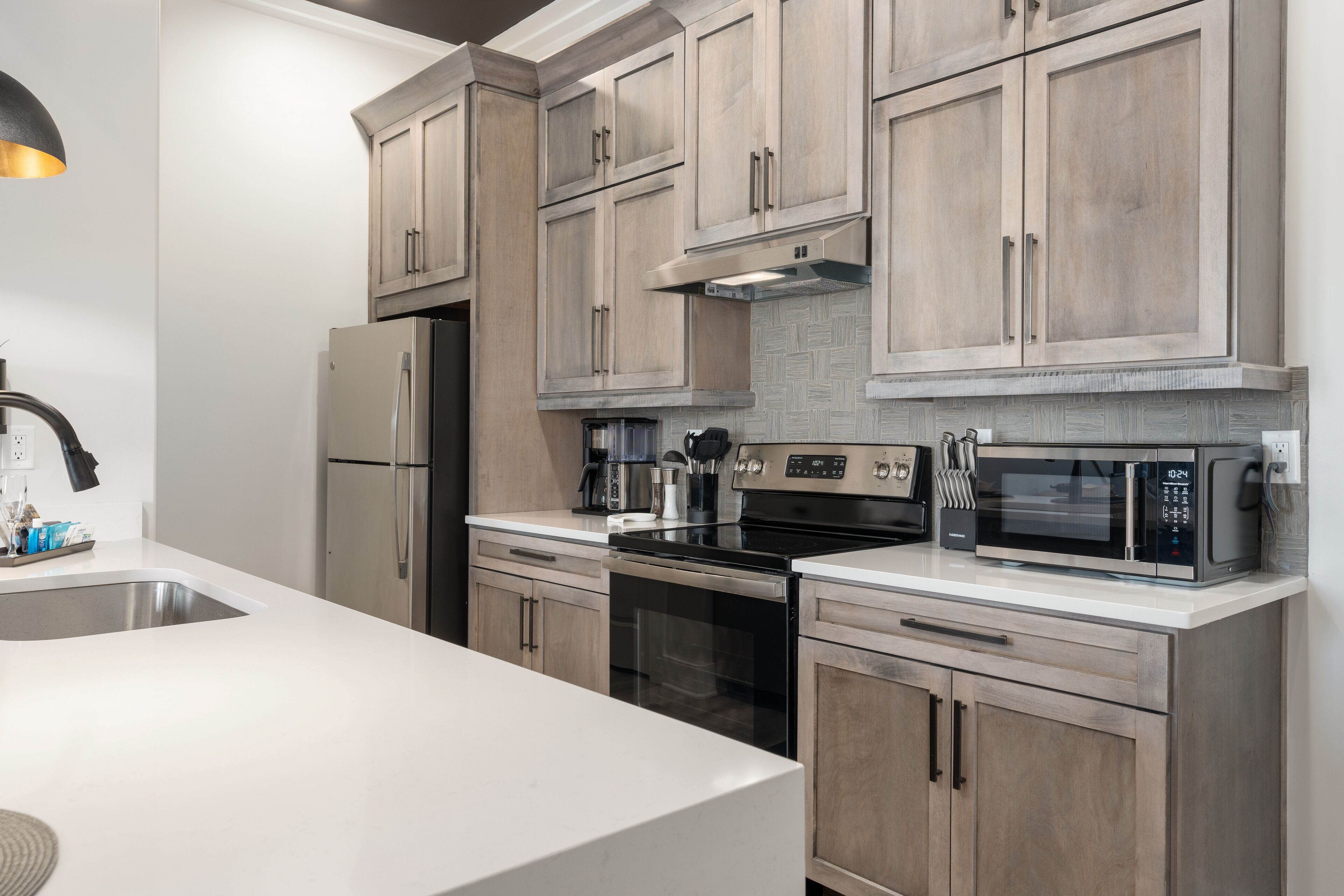 Una cocina moderna con armarios de madera clara, electrodomésticos de acero inoxidable y encimera blanca.