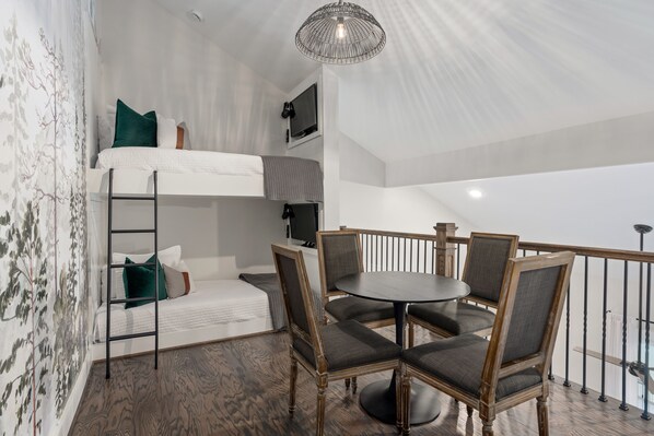 A loft-style bedroom with a bunk bed, a dining table with chairs, and a chandelier. - 2 Bedroom Executive Suite + Bunk Bed Loft (Helena)