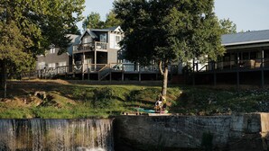 Een waterval, een houten terras en een gebouw met een balkon.