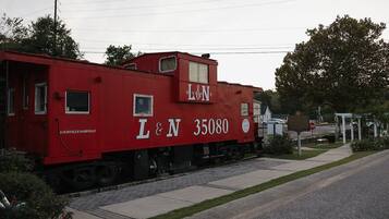 A red train car with 'L&N 35080' and 'Louisville-Nashville' written on it, parked on tracks near a road.