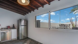 A kitchen with a stainless steel refrigerator, a dishwasher, and a window overlooking a patio with outdoor furniture. - Villa Winter Apt. 1 (Funchal)