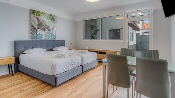 A modern hotel room with a large bed, a desk, and a dining area. - Villa Winter Apt. 1 (Funchal)