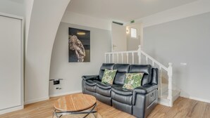 A modern living room with a leather sofa, a wooden coffee table, and a staircase with white railings. - Villa Winter Apt. 1 (Funchal)