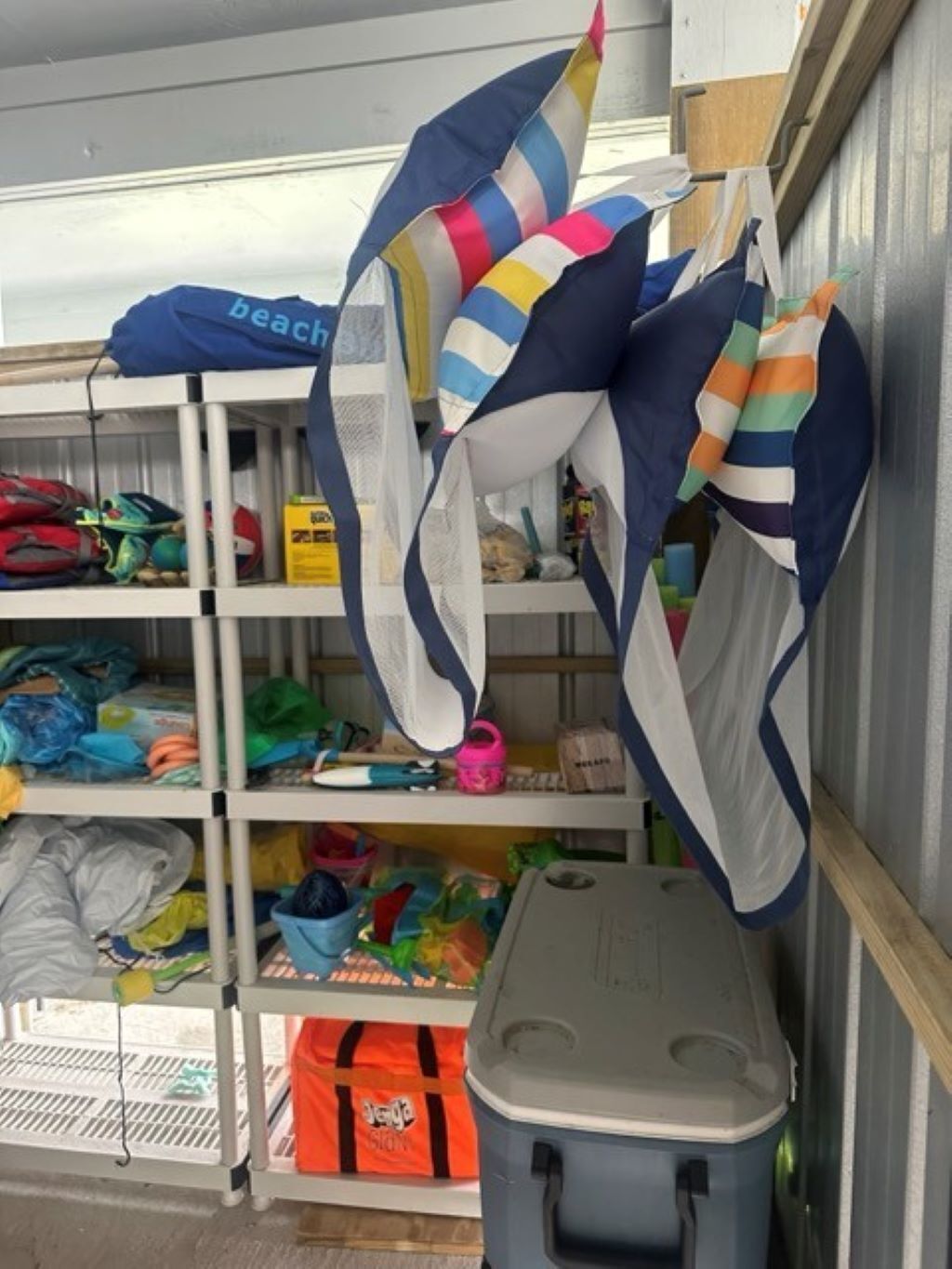 A storage area with shelves containing various items like bags, a trash bin, and a small table.