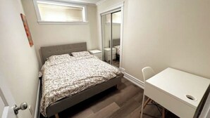 A bedroom with a bed, a desk, and a window.