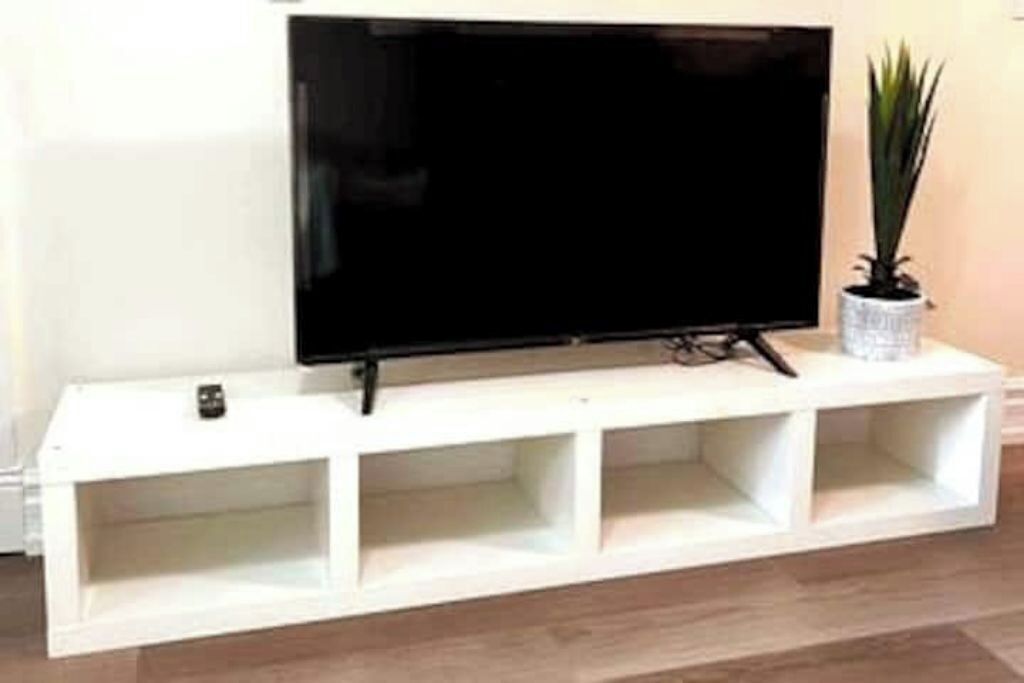 A white entertainment unit with a flat-screen TV mounted on top.