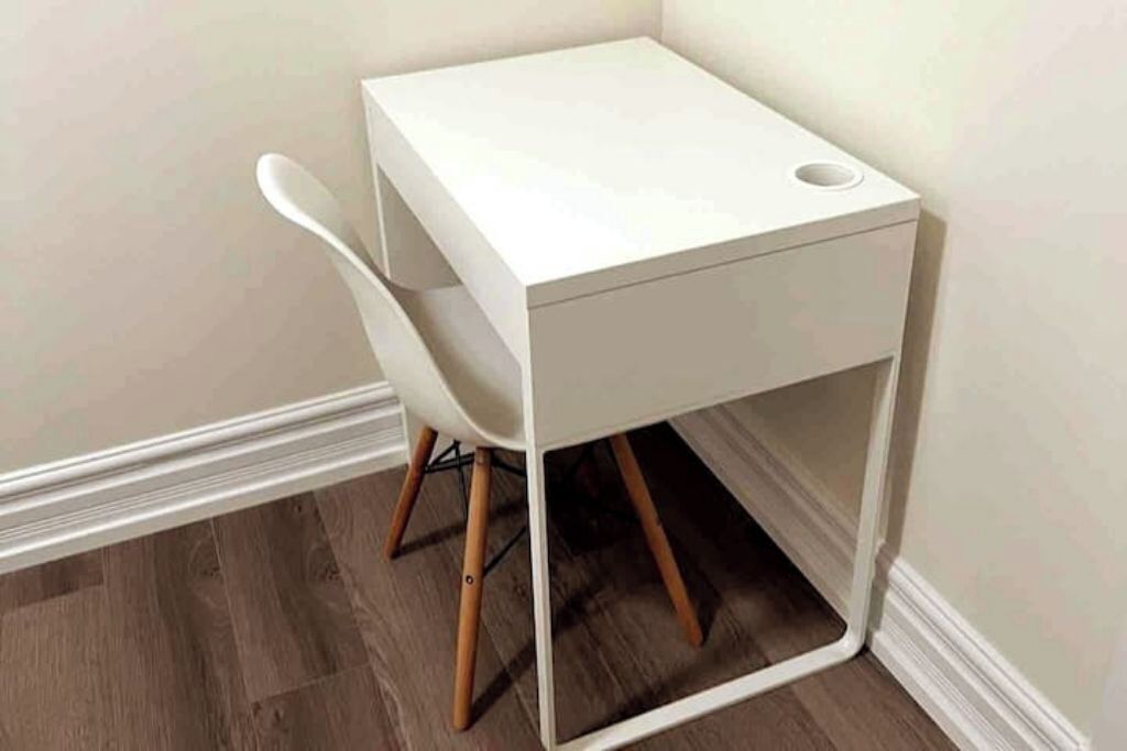 Una mesa blanca de madera con un marco cuadrado y una silla blanca.