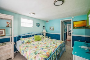 Quarto com cama, cômoda, escrivaninha e janela.