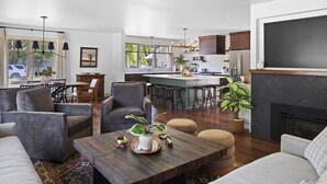 Un vaste espace de vie agrémenté d’une grande table basse en bois, de sièges confortables et offrant une vue sur la cuisine et la salle à manger.