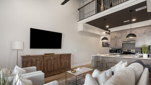 A modern living room with a sofa set, a coffee table, and a flat-screen TV mounted on the wall. - 2 Bedroom Suite + Loft, Second Floor (Helena)