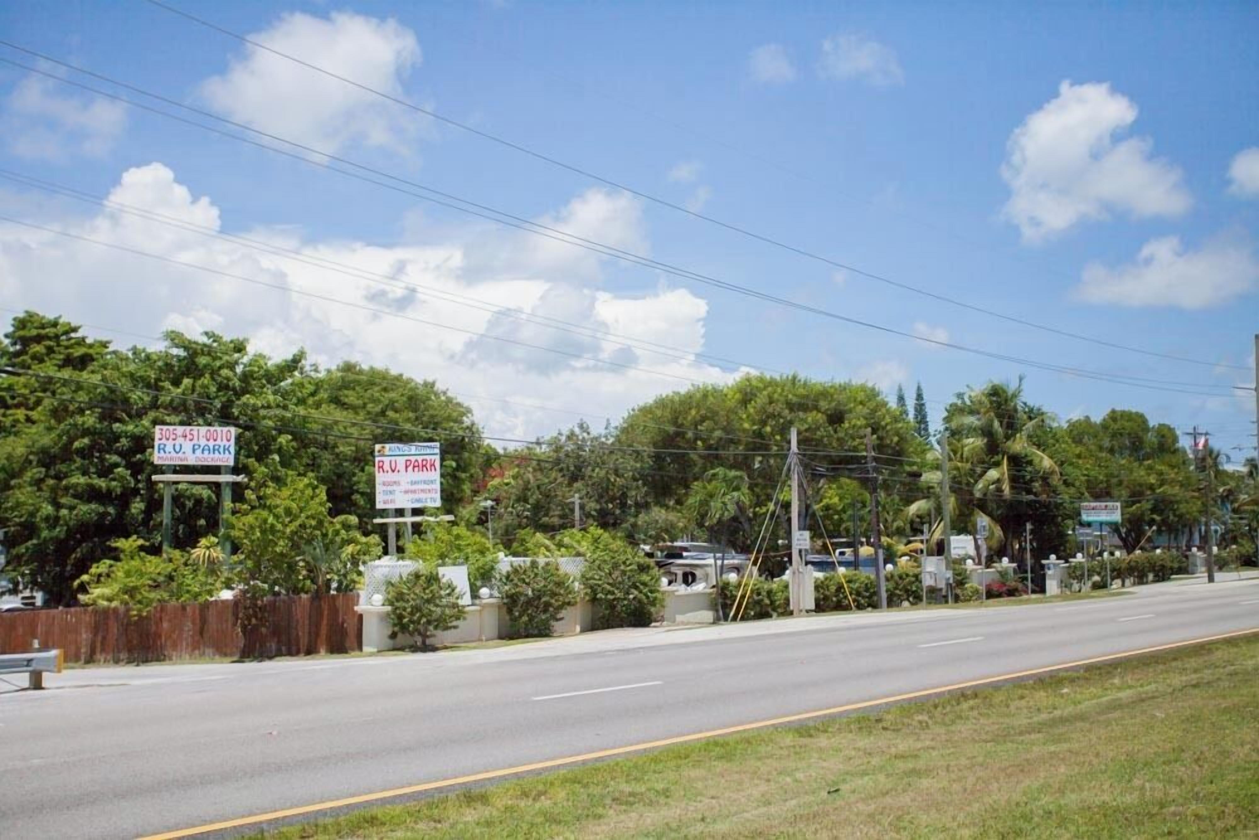 Vista de la calle con una carretera despejada, un cartel de R.U. Park y abundante vegetación.