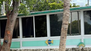 A building with a stone wall and windows. - Captain Jax (Key Largo)