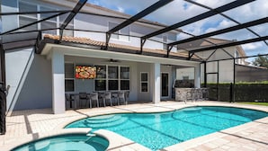 A swimming pool with a hot tub, a covered patio area, and outdoor seating. - Luxury Windsor Haven: 6BR Private Pool & Game Room (Kissimmee)