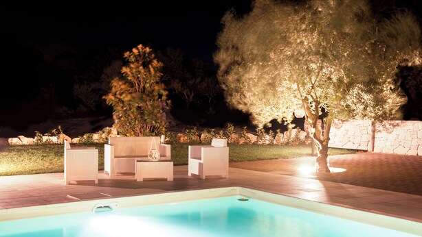 Una piscina con sillones de descanso y un árbol.