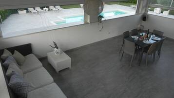 Una sala de estar moderna con un sofá, una mesa de comedor y vistas a una piscina.