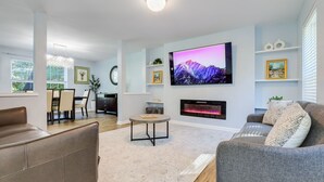 Uma sala de estar moderna com televisão de tela plana, lareira e assentos confortáveis.