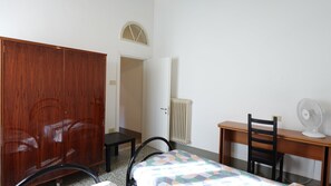 A room with a bed, a desk, a chair, a wardrobe, and a radiator. - Oasis 2: Relaxation and History in Pisa (Pisa)