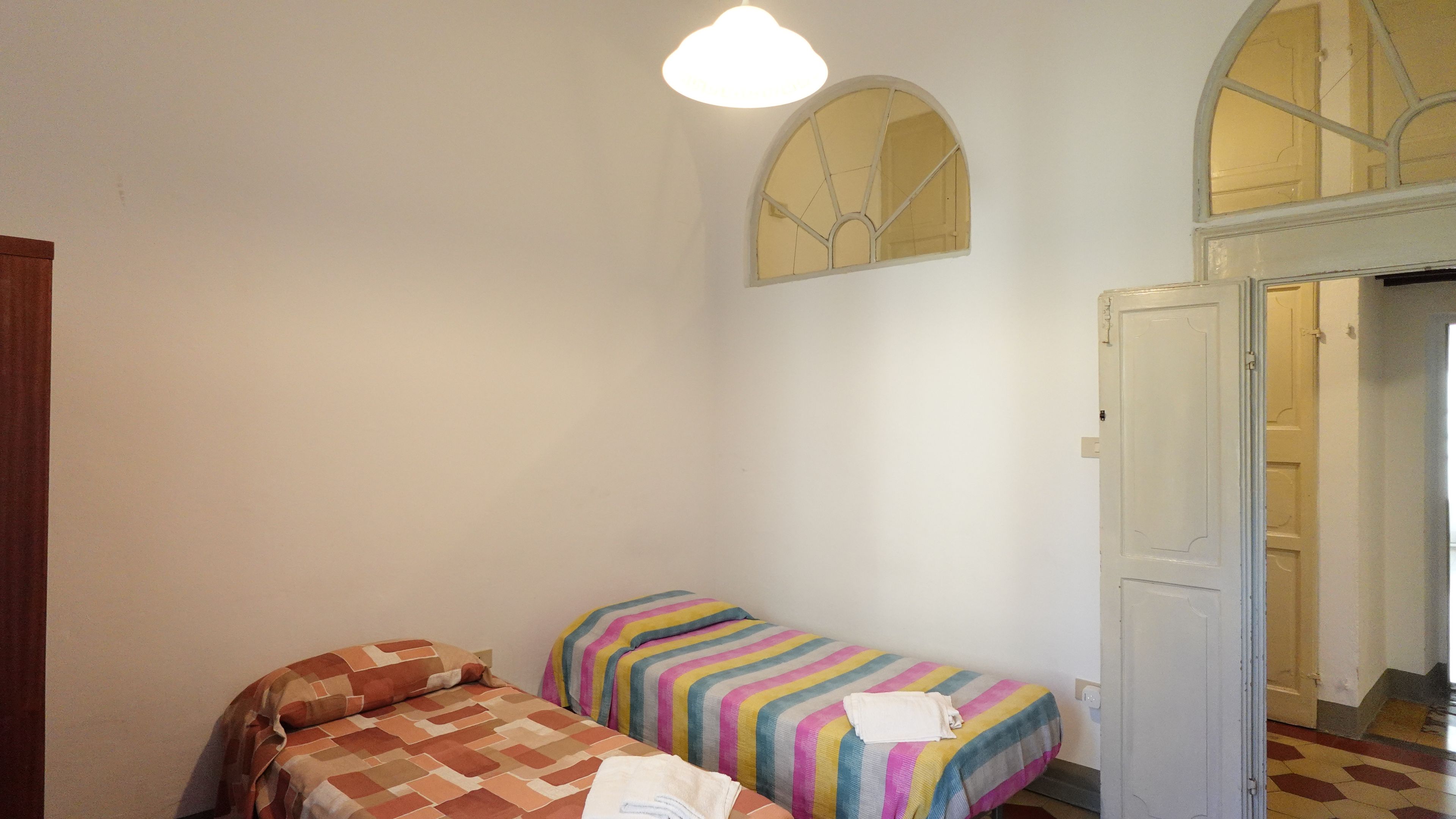 A room with two beds, a window with a view, and a door leading to another room.
