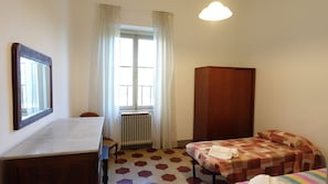 A room with a bed, a desk, a radiator, and a wardrobe.