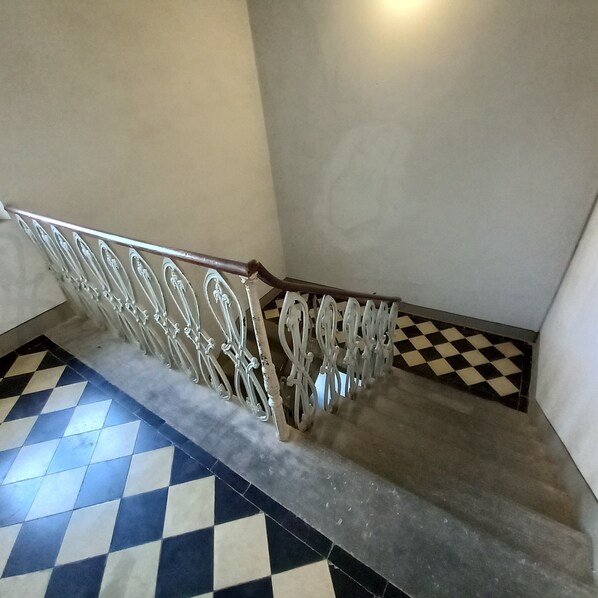 A staircase with a checkered floor pattern and a metal railing.