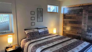 Une chambre à coucher avec un lit, des lampes de chevet, une fenêtre et une tête de lit en bois.