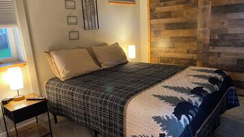 A bedroom with a bed, bedside table, lamp, and wall decor.