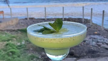 A cocktail in a glass with a beach view in the background.