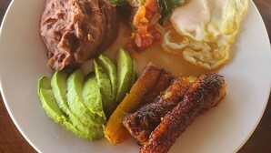A plate of food with beans, avocado, bacon, eggs, and a vegetable mix. - Beachfront Casa Maya resort (Tamanique)