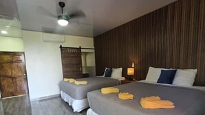 A hotel room with two beds, grey bedding, wooden panel walls, and a grey tiled floor. - Beachfront Casa Maya resort (Tamanique)