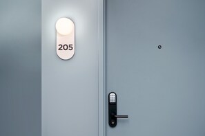 Eine moderne Tür mit Zahlenschloss und beleuchteter Nummerntafel mit der Aufschrift '205'.