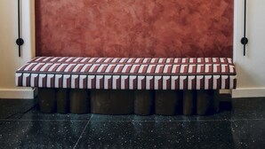 A wall with a large arched design and a bench with a striped pattern. - The Neighborhood Hotel - Little Italy LI (Chicago)