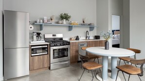 Een moderne keuken met roestvrijstalen apparatuur, houten kastjes en een ronde eettafel met stoelen.