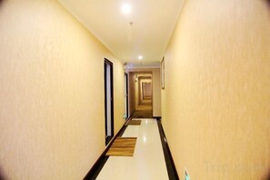 Un pasillo de hotel con piso alfombrado, puertas a ambos lados y una lámpara en el techo.