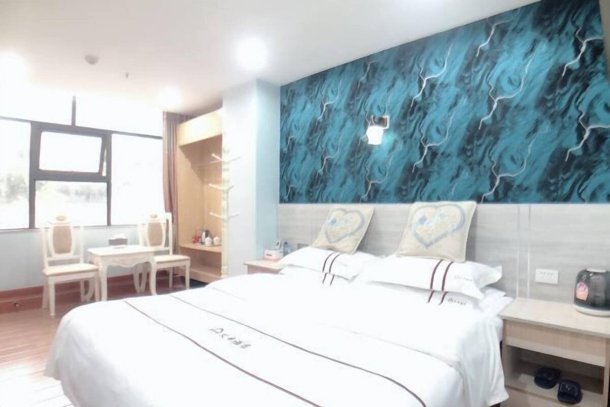 A hotel room with a bed, bedside table, nightstand, and a window with a view.