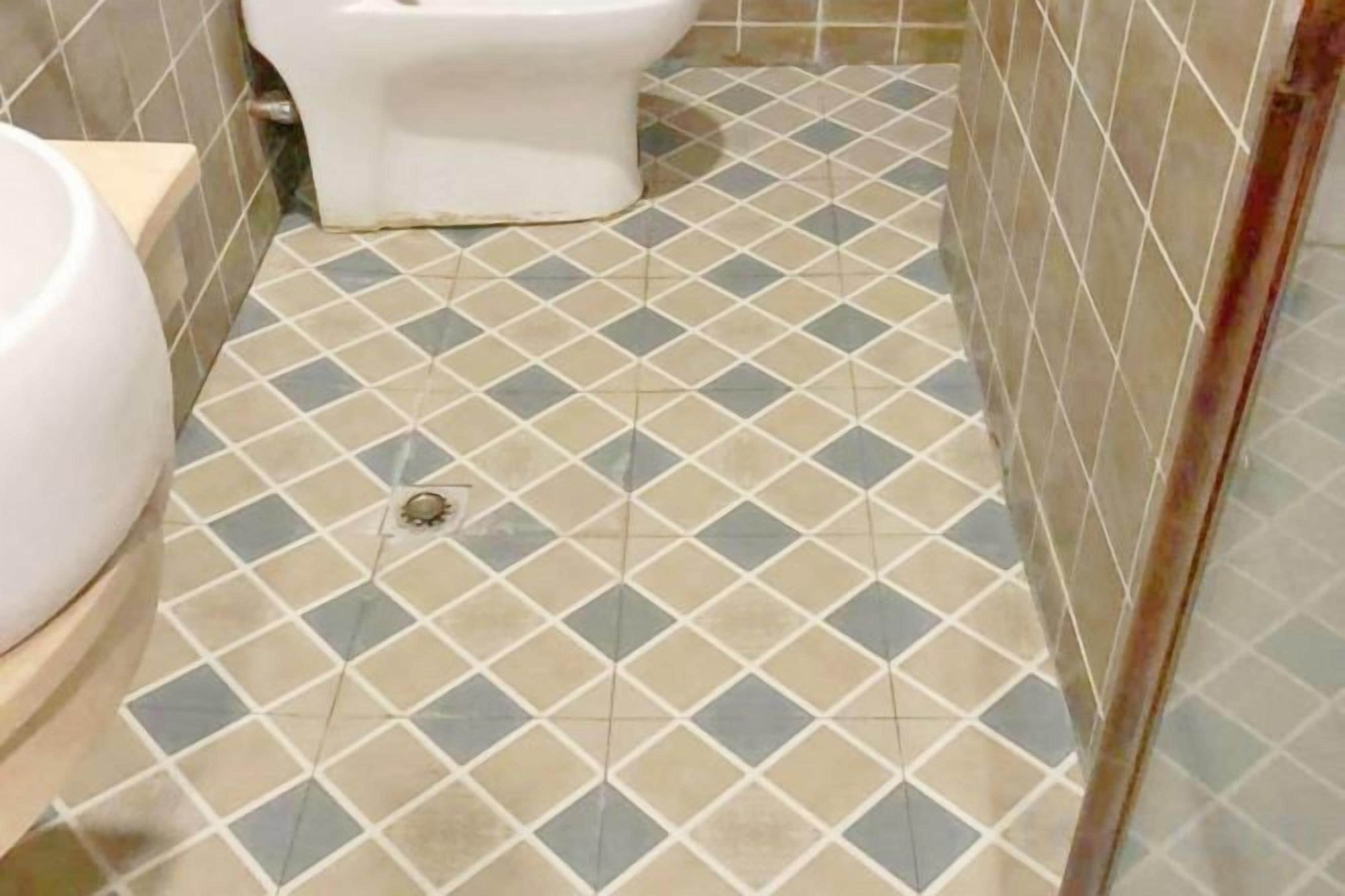 A bathroom with a tiled floor, a toilet, and a sink.