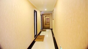A long, narrow hallway with cream-colored walls and a glossy white floor. - AiXi Traving with hostel (Chongqing)
