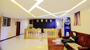 A hotel lobby with a reception desk, a sofa, and a patterned wall.
