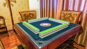 A room with a table set up for a game, featuring a green and white board game, a clock, and a decorative mirror. - AiXi Traving with hostel (Chongqing)