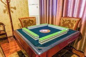 A room with a table set up for a game, featuring a green and white board game, a clock, and a decorative mirror. - AiXi Traving with hostel (Chongqing)