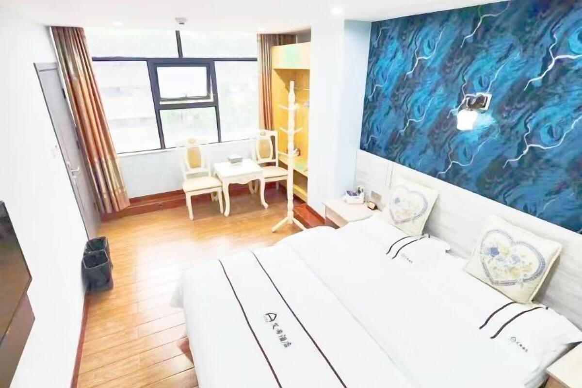 A hotel room with a bed, a desk, a chair, and a large window.