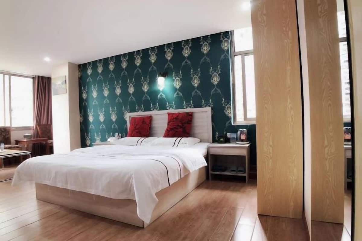A bedroom with a large bed, a nightstand, and a wooden wardrobe.