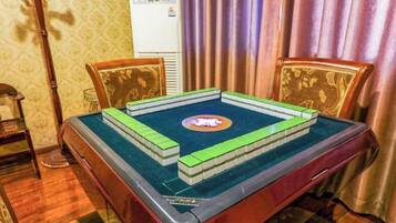 Una habitación con una mesa dispuesta para un juego, una silla, una lámpara y un aire acondicionado instalado en la pared.