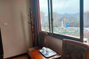 A room with a dining table set with a tray, chairs, and a view of a cityscape through large windows. - AiXi Traving with hostel (Chongqing)