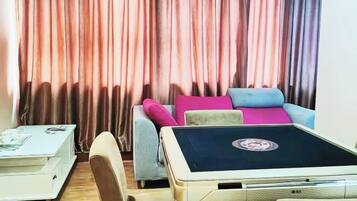 Una habitación con sofá, una mesita y cortinas.
